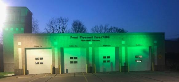 The Point Pleasant Fire and EMS station at dusk with its bays lit green
