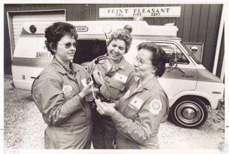 Three members in department jumpsuits beside an ambulance outside the Point Pleasant Vol. Fire Dept. station