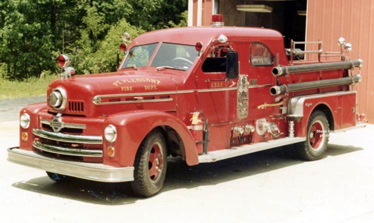 A red open-cab pumper outside the station