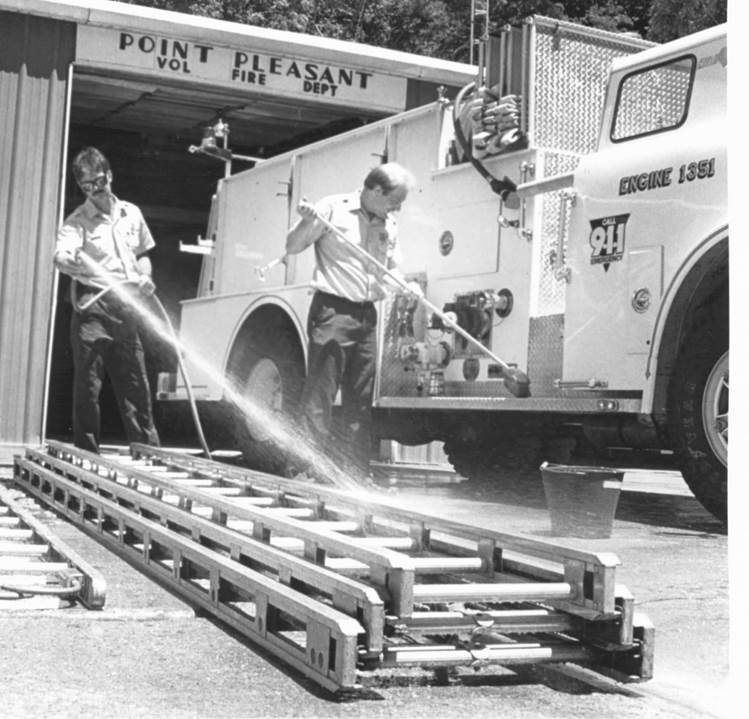 Two members washing ground ladders on the apron outside the Point Pleasant Vol. Fire Dept. bays